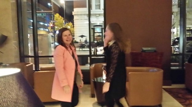 Image: slightly blurry photo of white woman in pink coat dancing with blond girl (from photo 2 above) in a black dress.