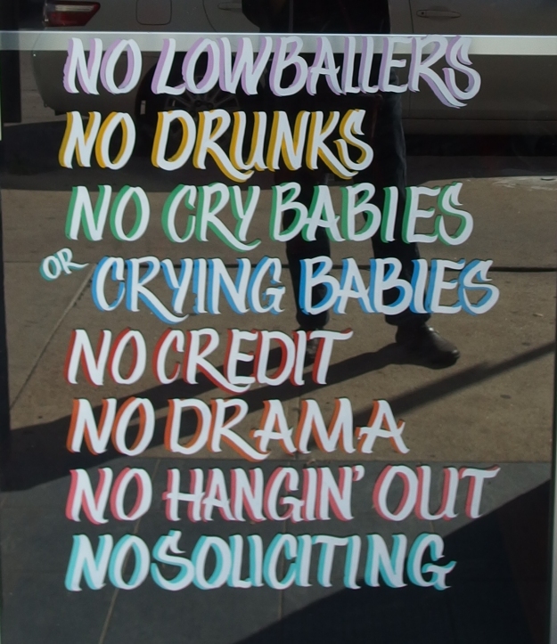 Image: Store window with painted text that reads, "No lowballers; no drunks; no crybabies or crying babies; no credit; no drama; no hangin' out; no soliciting."