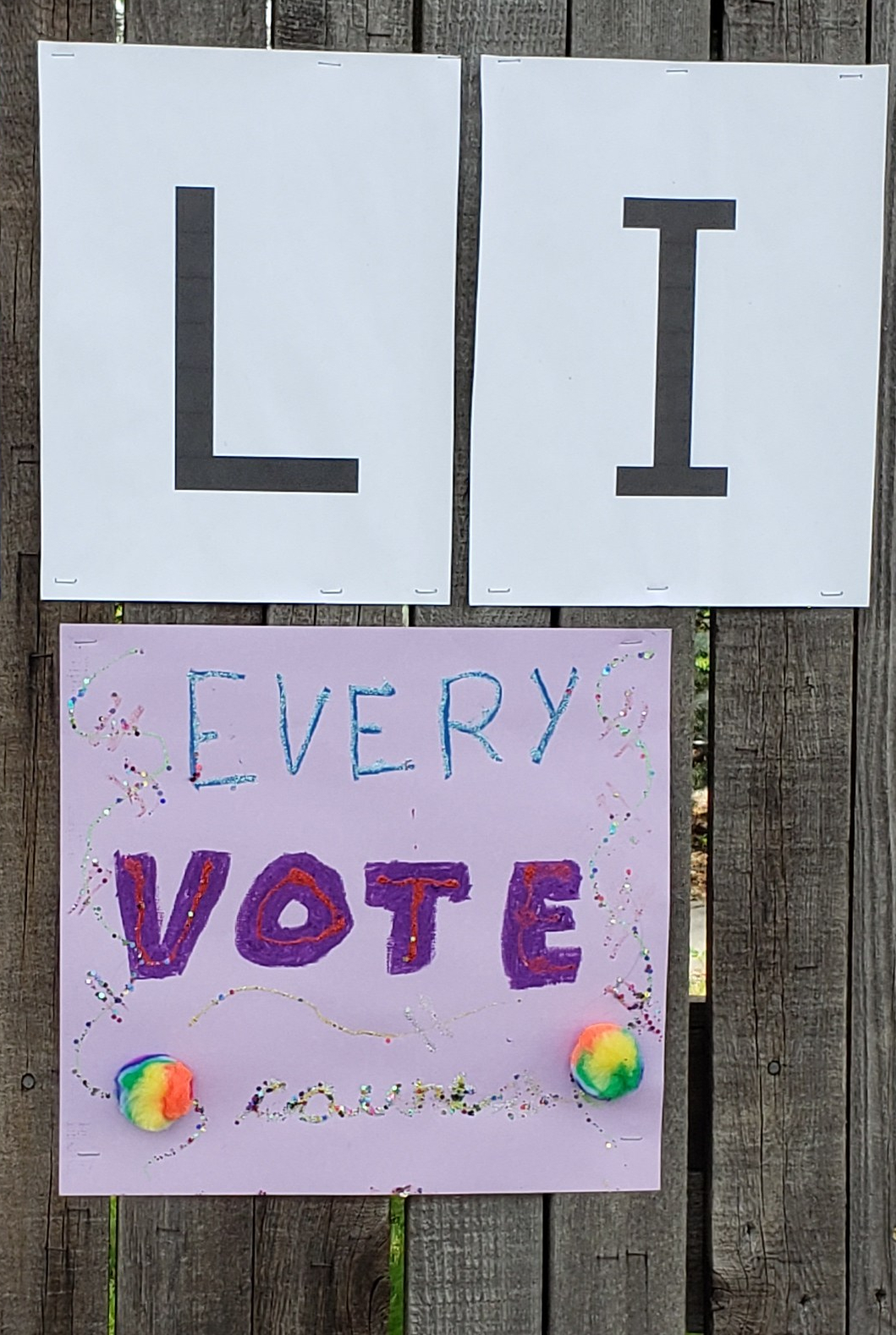 Purple construction paper sign that reads "Every Vote counts" in various colors and giltter, with two rainbow cotton balls.